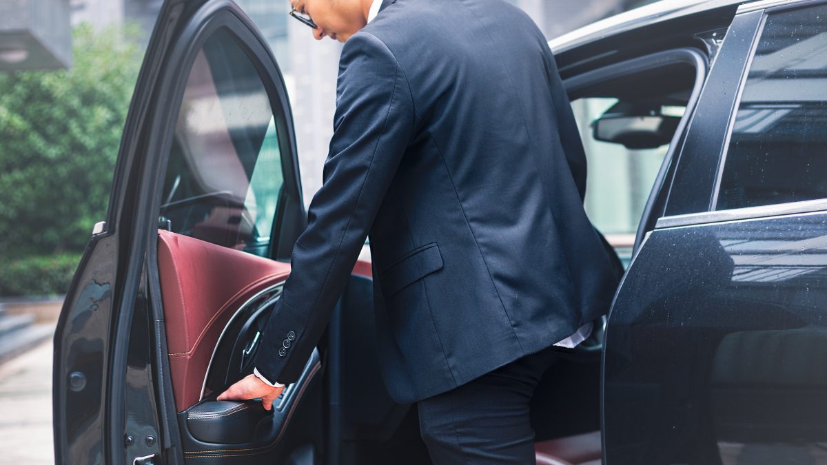 detail shot of young businessman sitting into his car.