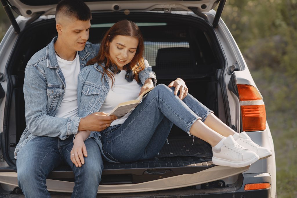 Couple sitting in a trunk. A beautiful girl is having a good time with her boyfriend.